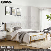 A queen-sized metal bed with a white headboard and gray upholstery in a room with a light interior.